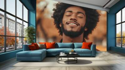 A young Black man with an afro smiles with his eyes closed. Wall mural