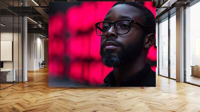 A young man wearing glasses looks up in front of a pink neon light. Wall mural