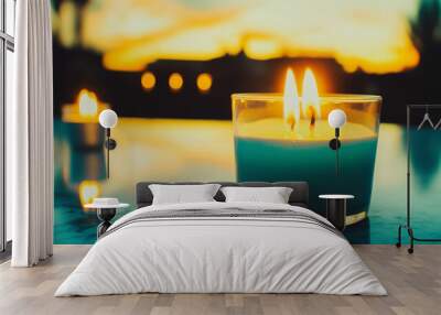 Teal candle with two flames burning brightly against a golden sunset backdrop. Wall mural