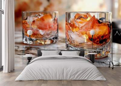 Two glasses of amber liquid with ice cubes on a marble surface. Wall mural