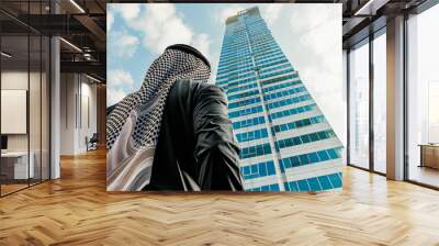 an arab man stands with his back to a modern tall building. construction and real estate investments Wall mural