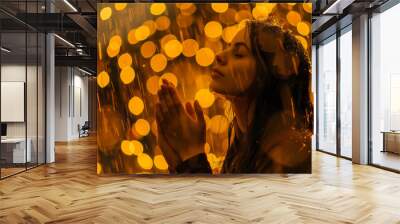 Young woman praying in the rаain with golden bokeh Wall mural