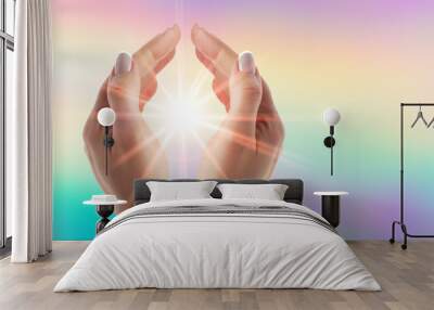 Healing hands with bright sunburst on rainbow background Wall mural