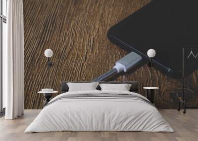 Mobile smart phones charging on wooden desk Wall mural