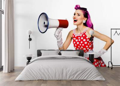 Beauty red haired woman holding megaphone, shout something. Girl in pin up style dress in polka dot, isolated over white background. Caucasian model posing in retro fashion vintage concept. Wall mural