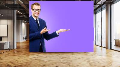 Business man businessman wear eye glasses spectacles, pointing show advertise, hold something, isolated against purple violet wall background with slogan text message empty area. Ad concept image. Wall mural