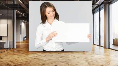 Businesswoman showing signboard, over grey Wall mural