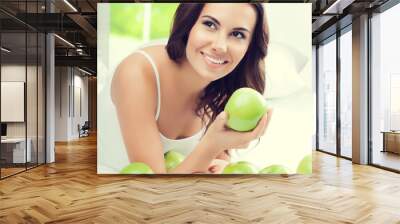 happy smiling woman with green apples, indoors Wall mural