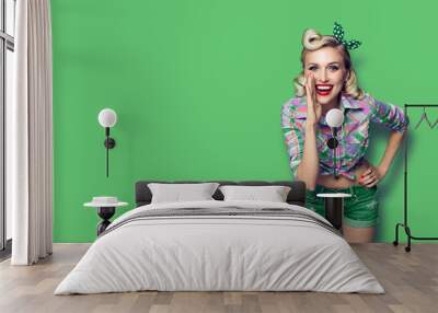 Photo of young happy smiling woman, dressed in pin-up style, over green color background Wall mural