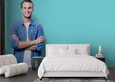 Portrait of young man standing in crossed arms pose, with copy space Wall mural