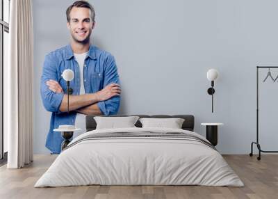 Portrait of young man standing in crossed arms pose Wall mural