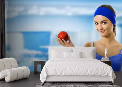 Woman in sportswear with apple, at gym Wall mural