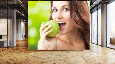 Young woman eating apple, outdoors Wall mural