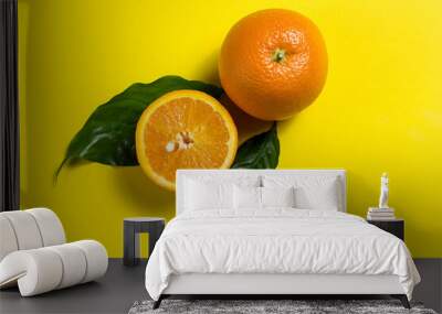 a whole orange and half an orange, and two green leaves Wall mural