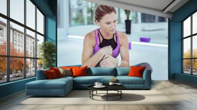 After athletic activity. Sad mature woman touching injured knee and posing on blurred background Wall mural