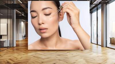 Asian beautiful female is applying eye serum Wall mural