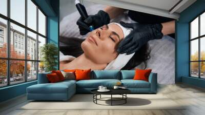 Beautician doing facial skin rejuvenation for beautiful client Wall mural