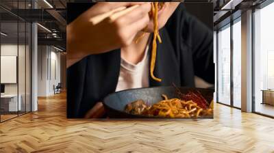 Close-up young Asian woman eating noodles in ginger-honey sauce with chopsticks Wall mural