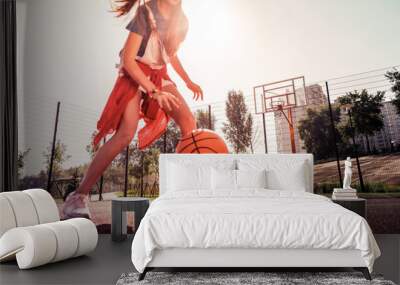 Experienced dark-haired young girl running around basketball playground Wall mural