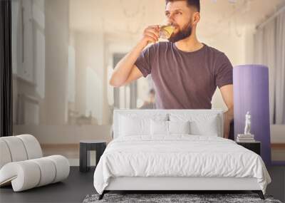 Handsome young man drinking tea in yoga studio Wall mural