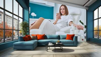 Happy smiling woman sitting in medicine armchair during medical procedure in beauty center Wall mural