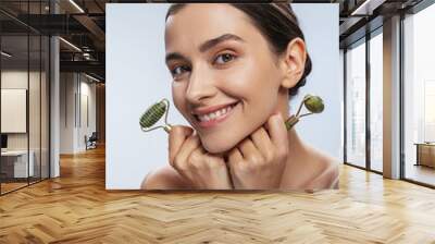 Happy young woman with two jade rollers Wall mural