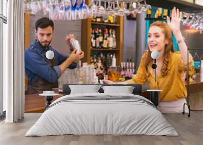 Hello. Cheerful emotional young girl sitting comfortably at the bar counter and feeling excited while waving to friends Wall mural