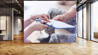 Here is what I noticed. Close up of female psychotherapist holding a clipboard and talking about psychology test results with a military patient. Wall mural