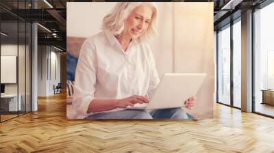 innovative retirement. positive minded senior woman wearing casual attire smiling while looking at a Wall mural