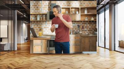 Let me check. Cheerful man turning head to laptop while reading news and standing in the kitchen Wall mural