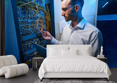 Male server administrator inserting cable into network switch Wall mural