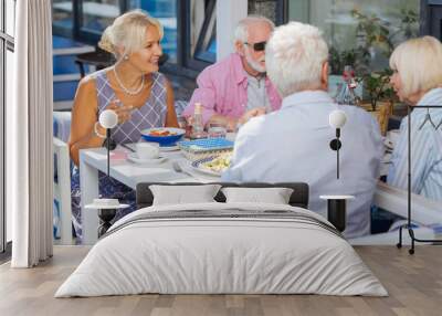 Meeting of friends. Nice aged people sitting at the table while having dinner in the restaurant Wall mural