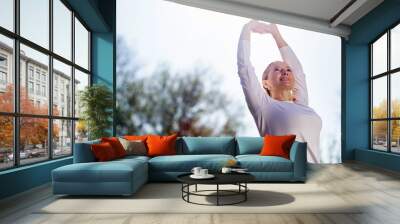 Morning gymnastics. Nice cheerful woman holding her hands up while doing morning exercises Wall mural