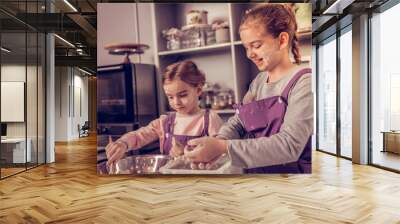 Positive young girls cooking together in the kitchen Wall mural