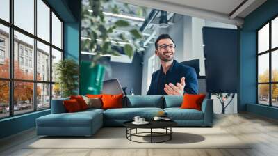 Smiling man gesticulating and sitting at table with laptop Wall mural