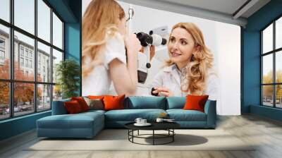 Sweet skillful ophthalmologist giving her patient instructions Wall mural