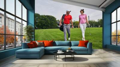 Trainer looking at a pleased female golfer Wall mural