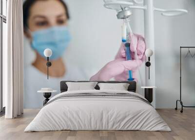 Woman in sterile gloves preparing for the intravenous therapy Wall mural