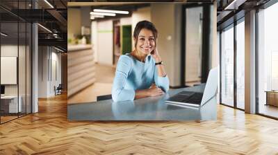 Young Caucasian female internet marketing specialist working at the laptop while surfing internet in modern interior workroom Wall mural