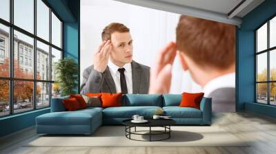 Young man fixing his hair in front of mirror Wall mural