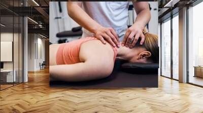 Young woman getting neck, head massage in therapy room. Masseur making chiropractic treatment Wall mural