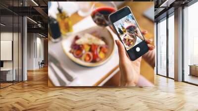 Young woman taking picture of food and wine with cellphone Wall mural