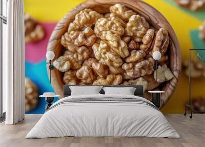 Close-up of fresh walnuts in wooden bowl on colorful background Wall mural