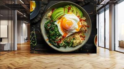 a savory breakfast bowl, including quinoa, sautéed spinach, avocado slices, and a poached egg, set on a dark wooden table with a side of hot sauce and a cup of herbal tea Wall mural