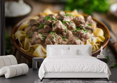 Russian beef stroganoff, with tender beef in a creamy sauce, served over egg noodles, garnished with parsley, on a rustic wooden table with a side of sour cream Wall mural