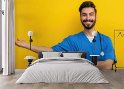 Smiling Hispanic male nurse in blue uniform pointing at camera. Wall mural