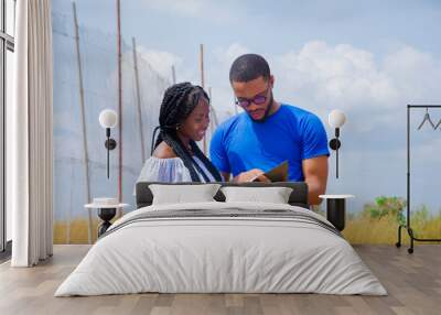 a young handsome african man and a beautiful african lady both studying their books outside Wall mural