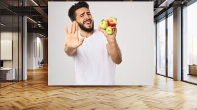 Cheerful man with apples in his hands in a white t-shirt fruits Wall mural