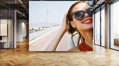 cheerful woman peeking out of the car window trip adventure lifestyle Wall mural