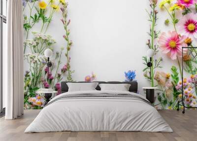 Colorful wildflowers arranged on a white background creating a natural floral frame Wall mural